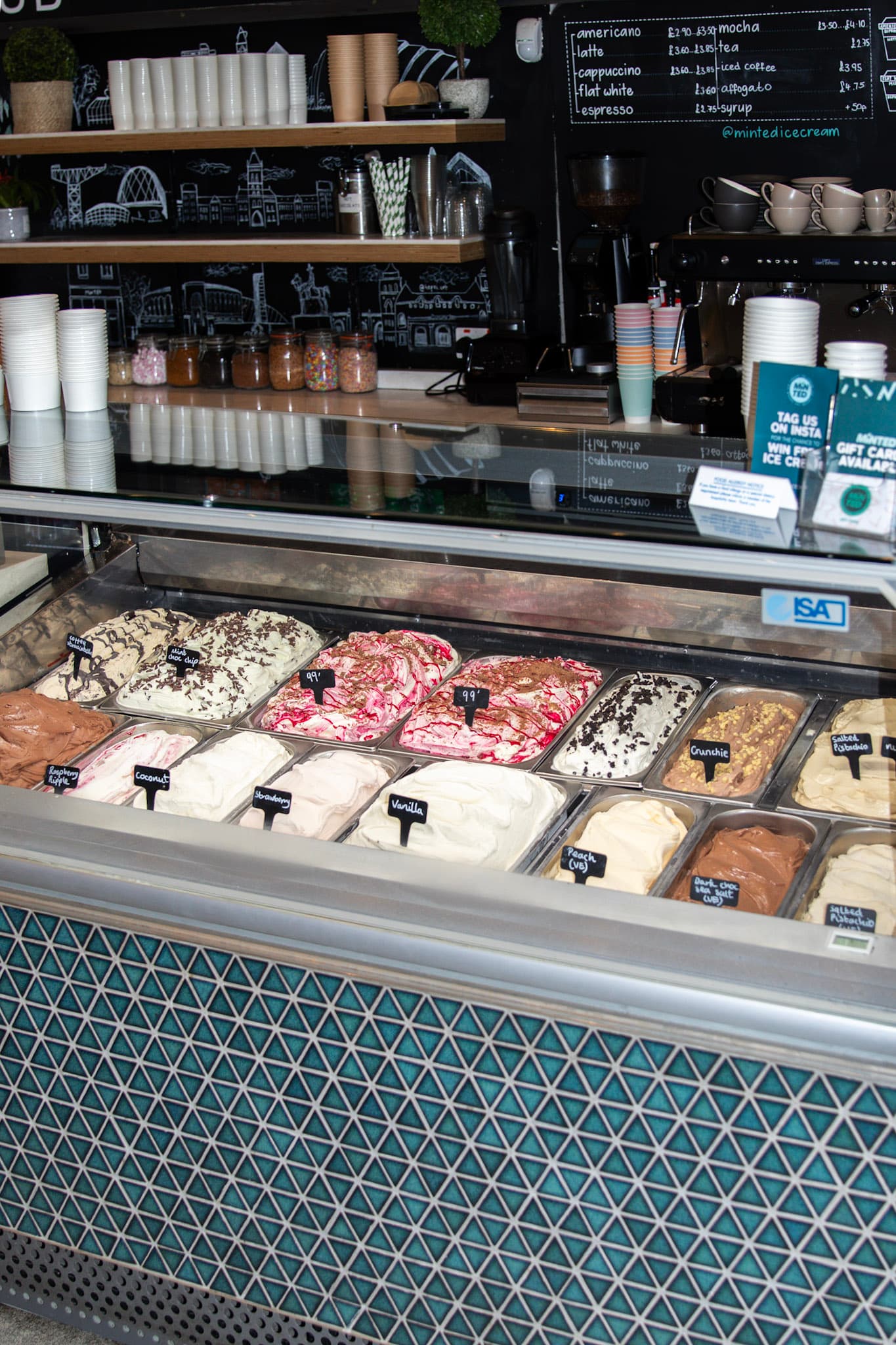 Minted Ice Cream counter with flavour pans in the glass case, chalkboard coffee menu, and espresso machine